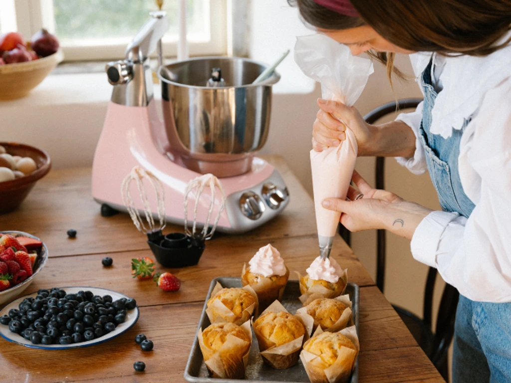 Dessertälskare som spritsar muffins med rosa frosting – skapat med Ankarsrum.