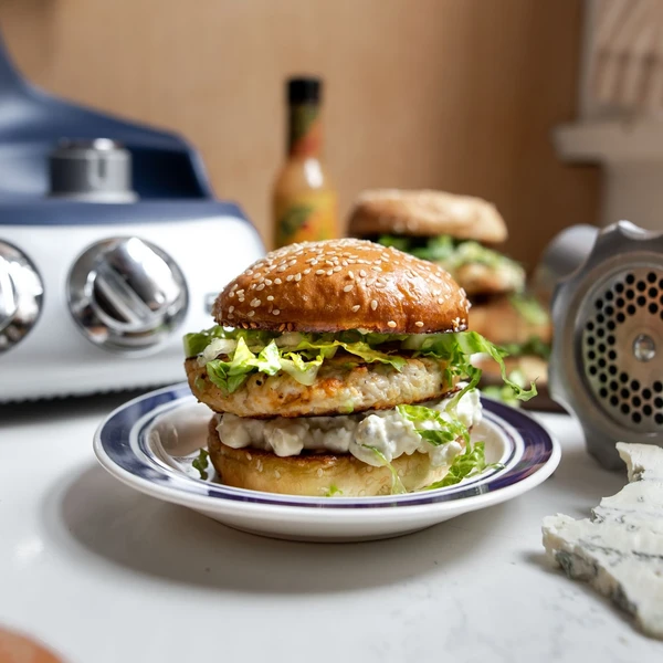 Juicy chicken burger with blue cheese sauce and lettuce on a sesame bun, made with Ankarsrum kitchen appliances.