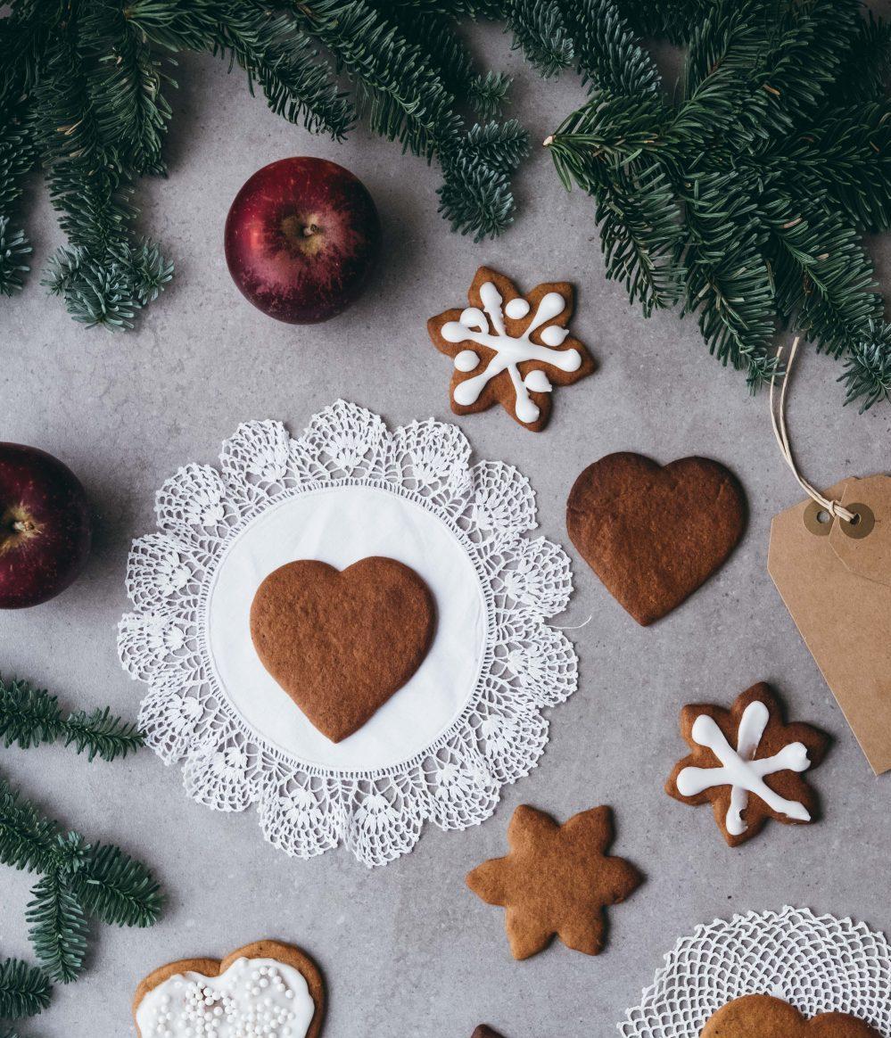 Heart-shaped Christmas gingerbread cookies surrounded with red apples