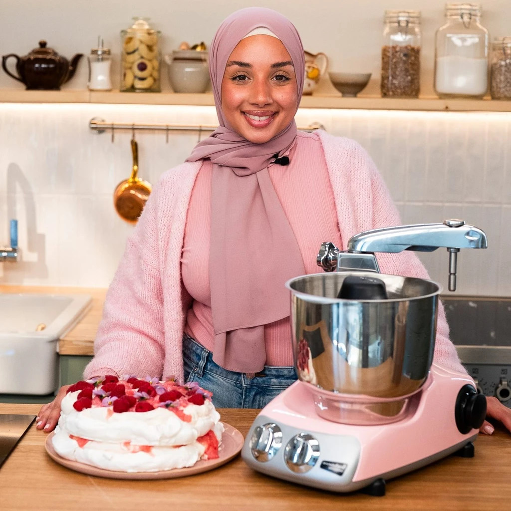     Dessertälskare som vispar grädde med Ankarsrum Assistent Original i ett rosa dessertkök.