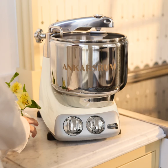 Ankarsrum Assistent Original in Creme Light on a light kitchen countertop in a yellow kitchen.