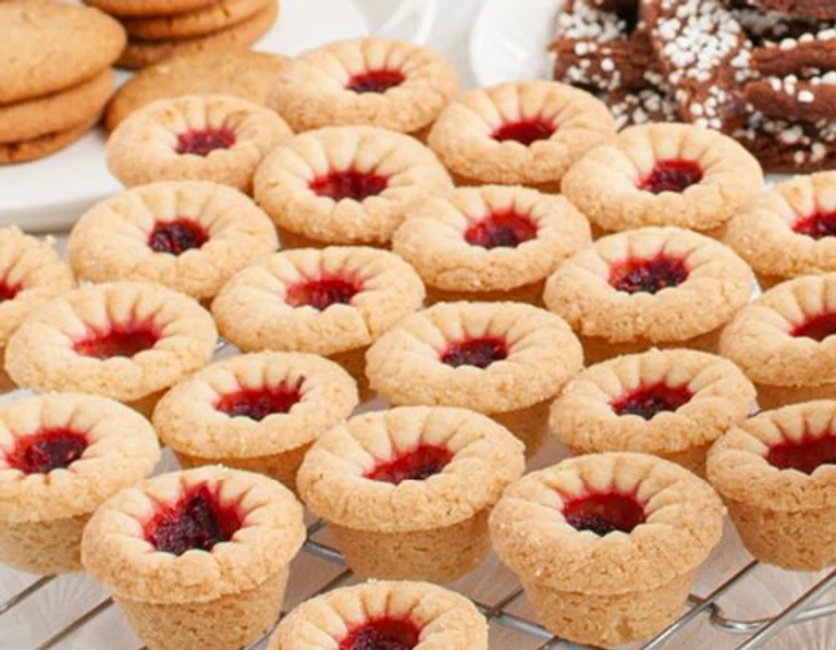 Freshly baked jam thumbprint cookies with red berry centers cooling on a wire rack, made with Ankarsrum stand mixer.