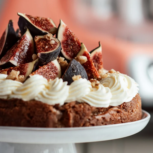 A delicious walnut cake with rich flavors and a creamy glaze topped with fresh figs.