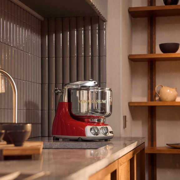 Ankarsrum Assistent Original dans la couleur Red sur un plan de travail dans une cuisine chaleureuse avec des éléments en bois.
