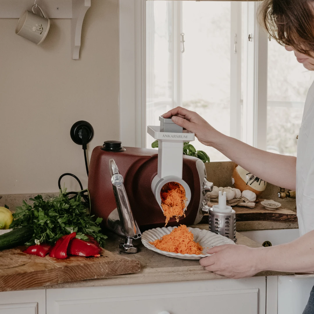 Person som river morötter med Ankarsrum grönsaksskärare som del av Go Green-paketet.