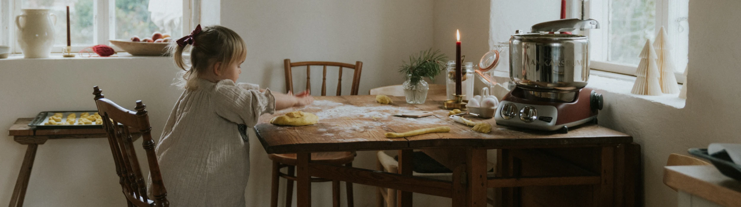 Julmys med barn som bakar lussekatter vid köksbordet med Ankarsrum köksmaskin.