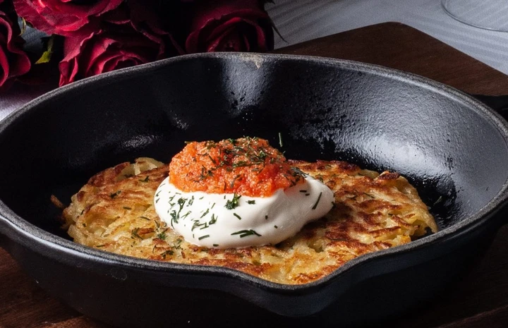 En bild på en råkaka som ligger på en svart tallrik. Den är toppad med creme fracihe och löjrom