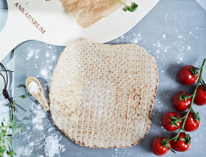 a picture of flatbread on baking steel. Tomatos on the side.