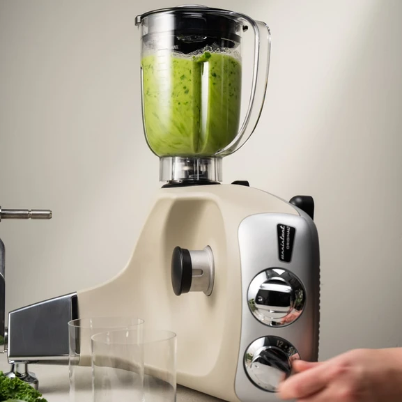 Ankarsrum Assistent Original mit montiertem Mixer, der grünes Gemüse mixt.