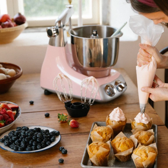 Dessertälskare som spritsar muffins med rosa frosting – skapat med Ankarsrum.