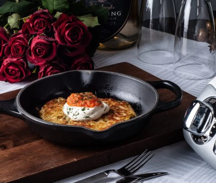 A picture of a raw cake on a black plate. It is topped with creme fracihe and onion roe.