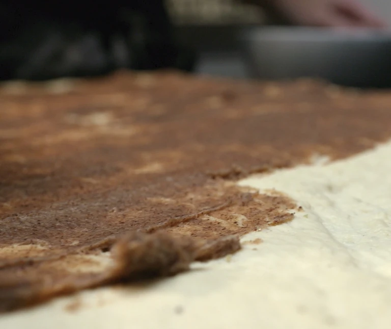 Rolled dough spread with cinnamon sugar filling on a floured surface, prepared using Ankarsrum stand mixer.