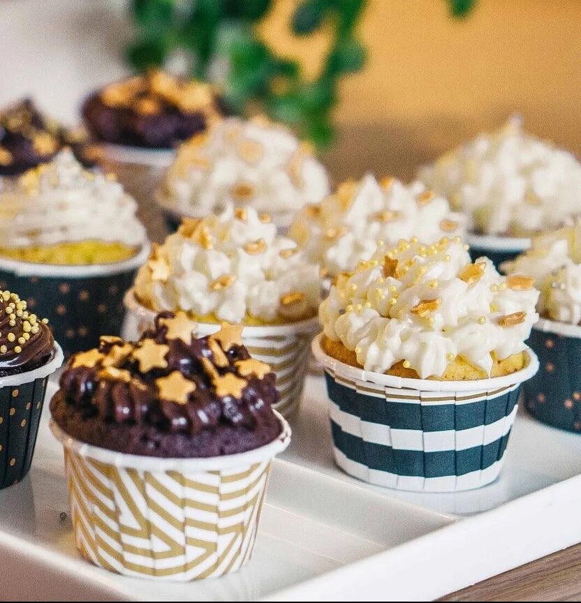 Assorted homemade cupcakes with whipped cream and chocolate frosting, decorated with gold stars, made with Ankarsrum stand mixer.
