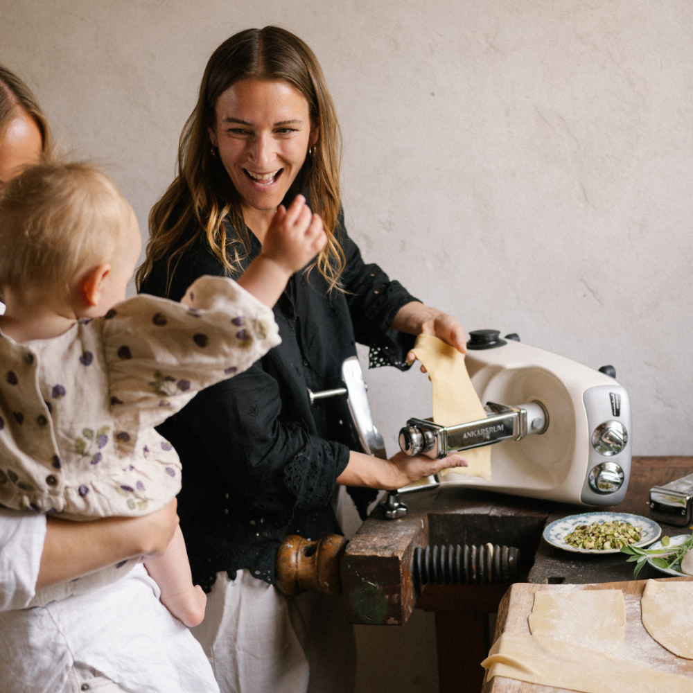 Familj som använder Ankarsrums pastavals i baspaketet för att göra pasta.