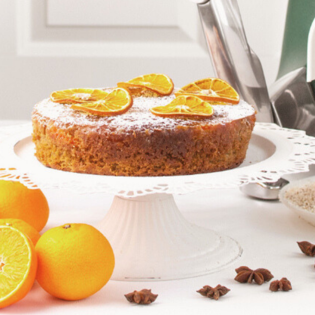 Glutenfri julkaka på fat, dekorerad med torkade apelsinskivor och florsocker.