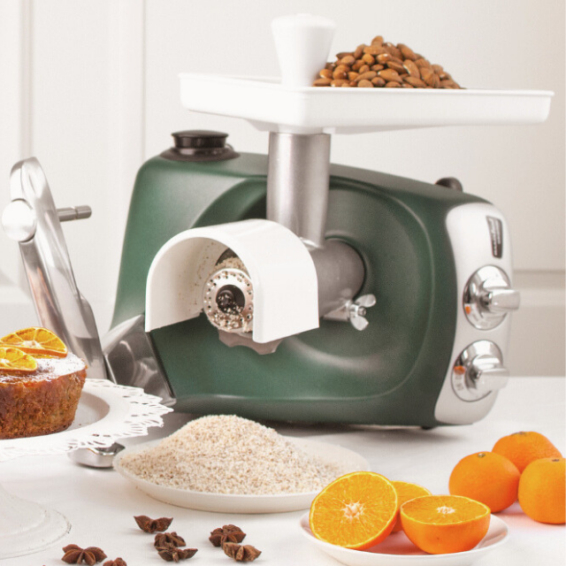 Ankarsrum Assistent Original med rivtillsats – malda nötter och bakverk på köksbänken.