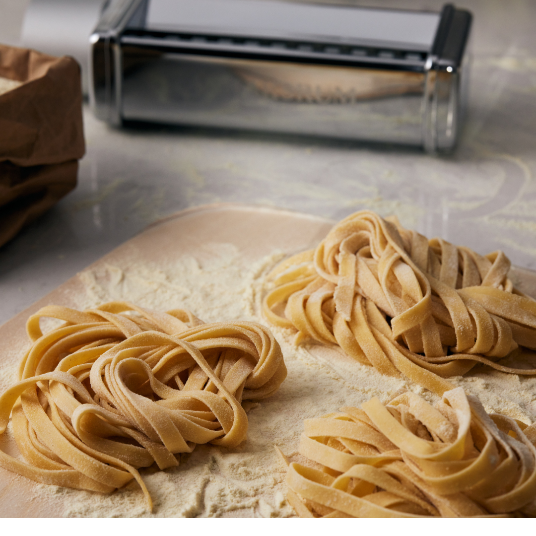 Nystan av hemmagjord fettuccine på mjölat bakbord, gjorda med hjälp av Ankarsrums pastavalsar.