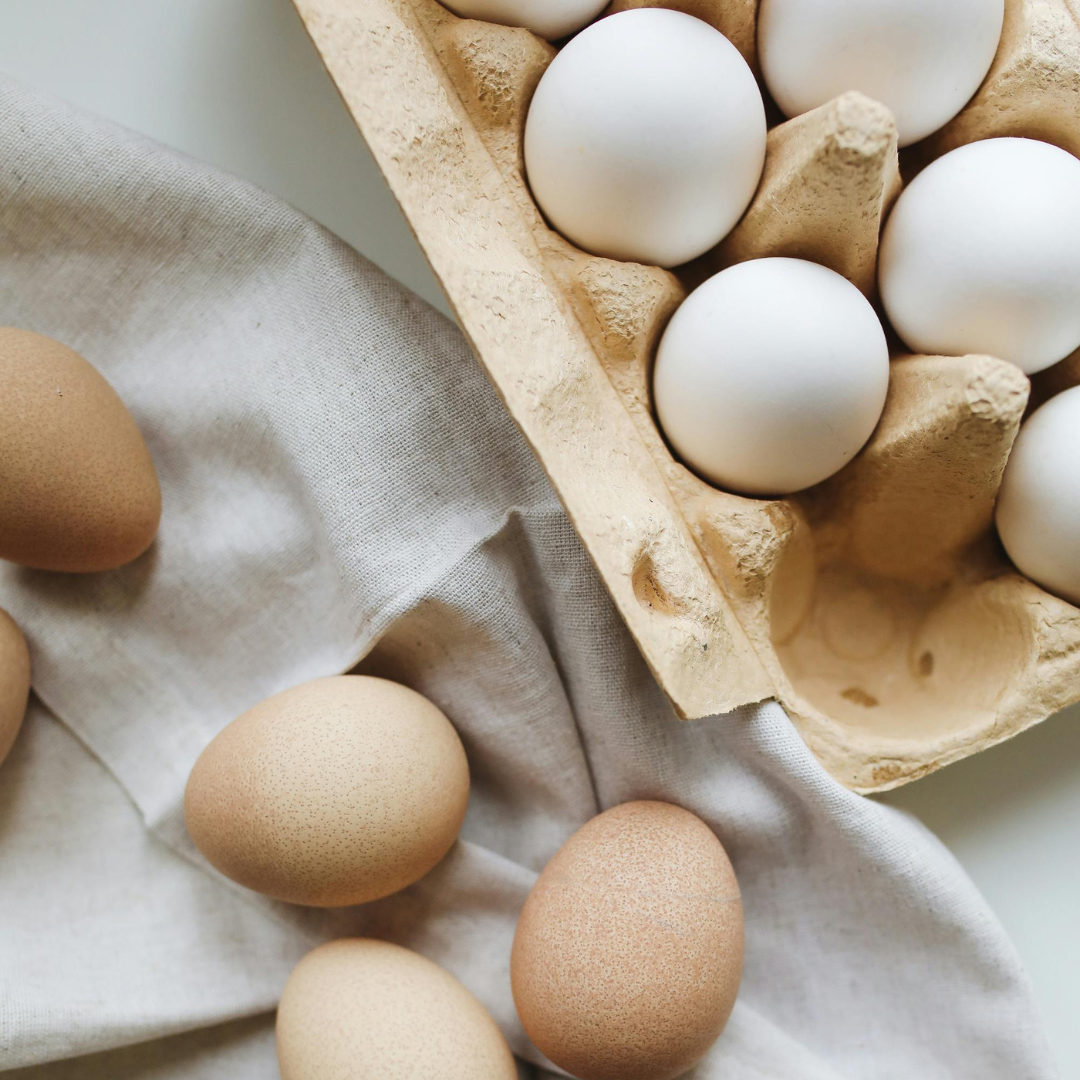 Ägg i naturliga nyanser på ljust tyg och i äggkartong, symbol för matlagning och bakning under vårens högtider.