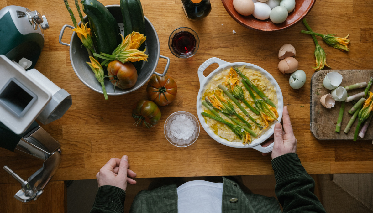 Ett färgglatt urval av vårens primörer uppdukade på en köksbänk bredvid en Ankarsrum köksassistent.