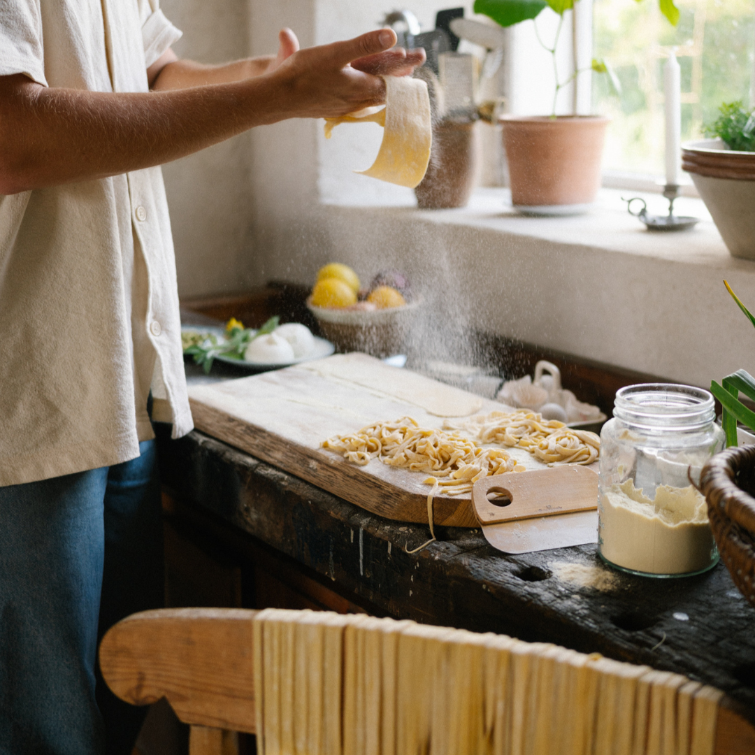 Handmade pasta shaped by hand on a floured work surface in a kitchen